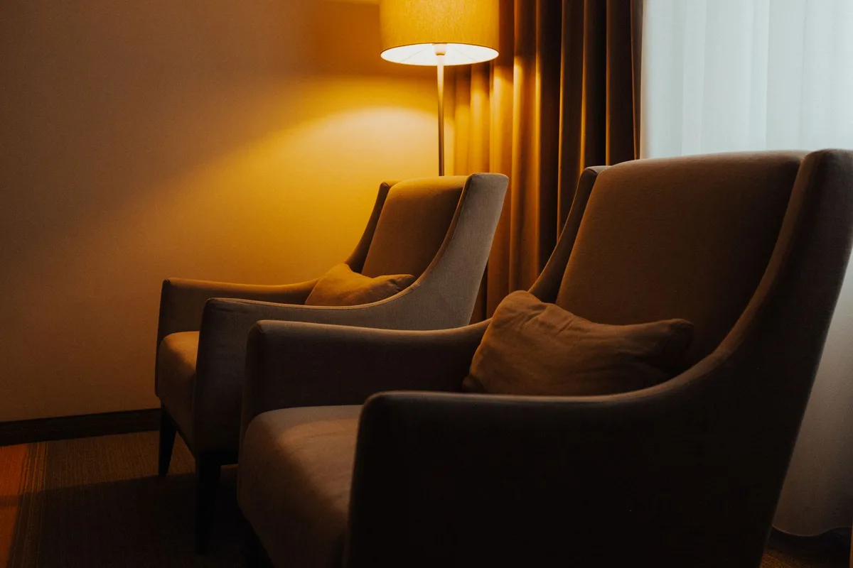 Lampe à poser portable sur une table près d'un fauteuil, utilisée pour la lecture